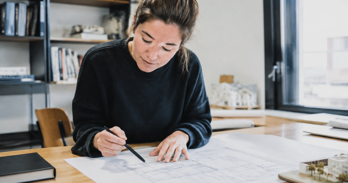 Architecte montrant plans maison sur table de travail