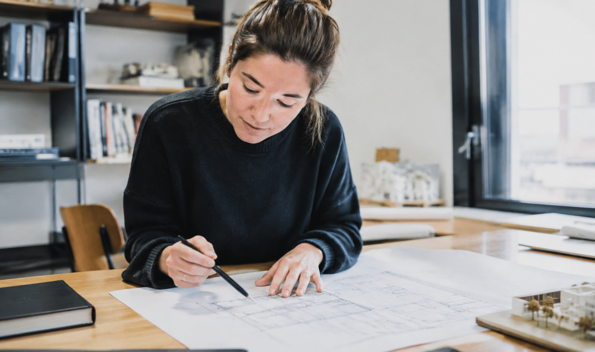 Architecte montrant plans maison sur table de travail