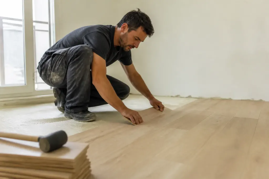 Artisan posant du parquet clair dans un salon