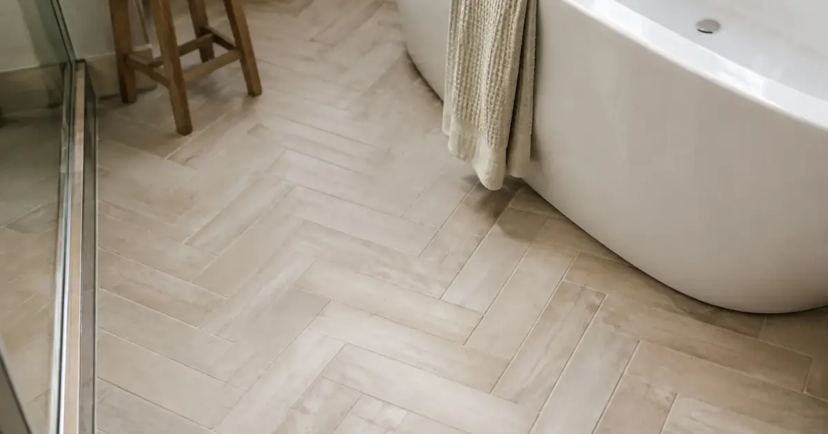 Dalles beige clair posees en chevrons pres baignoire blanche