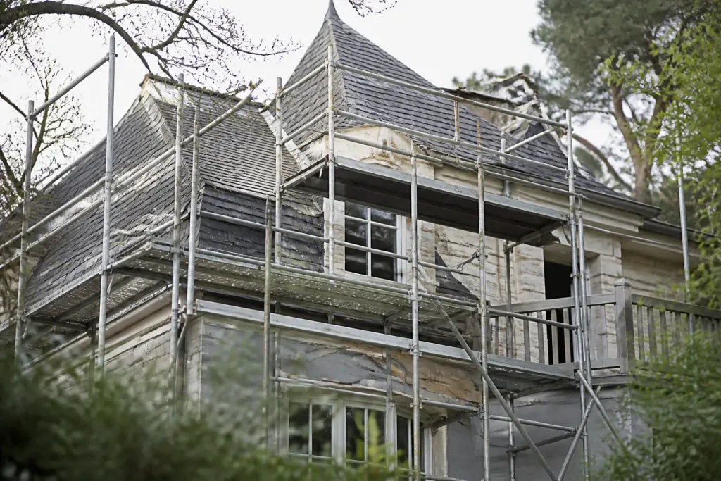 Echafaudage metallique devant une maison avec toit complexe