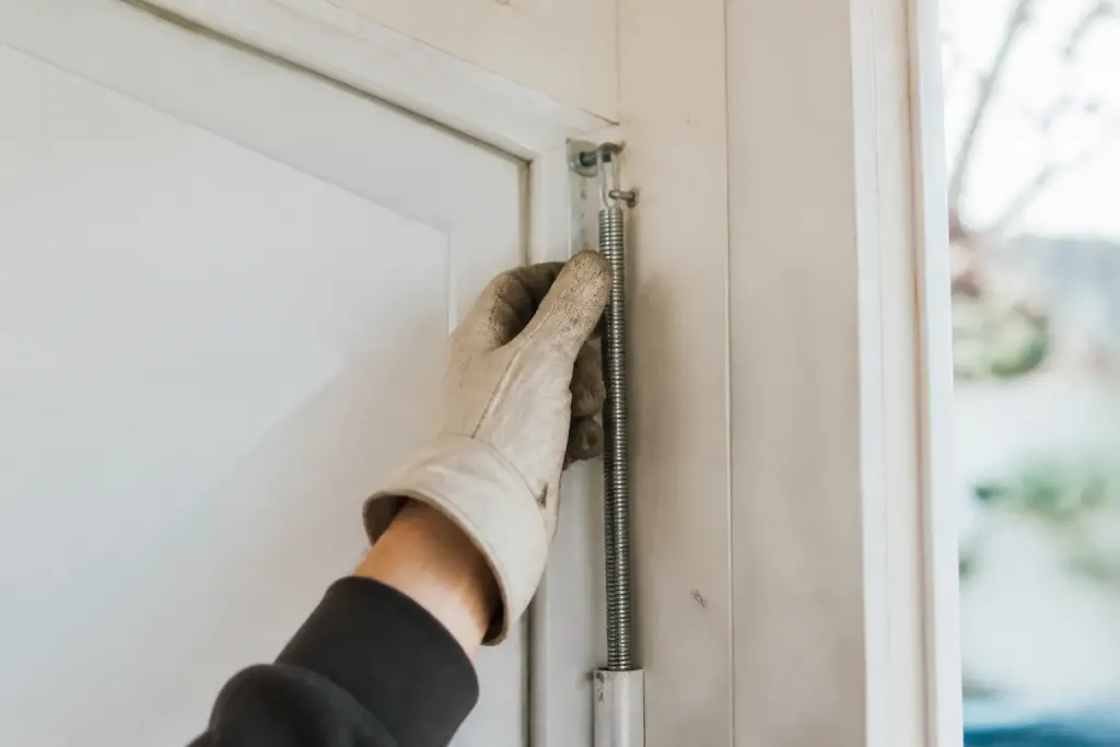 Main gantee ajustant un ressort metallique sur porte blanche
